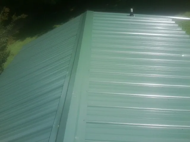 New green metal panels meeting at the ridge of a roof — Flat Roof Repair work by our crew in Red Rock