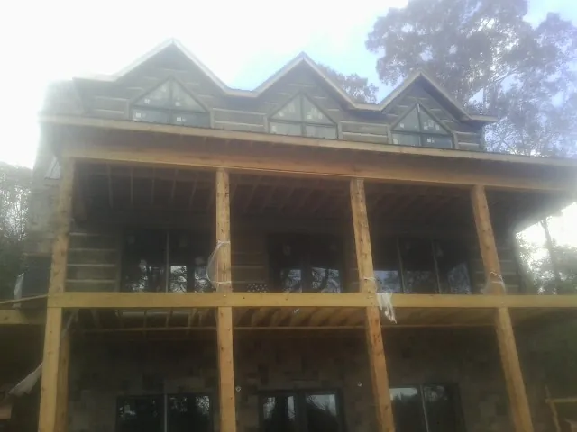 Dormers and porch framing on a large log home under construction — Roof Coating work by our crew in Red Rock