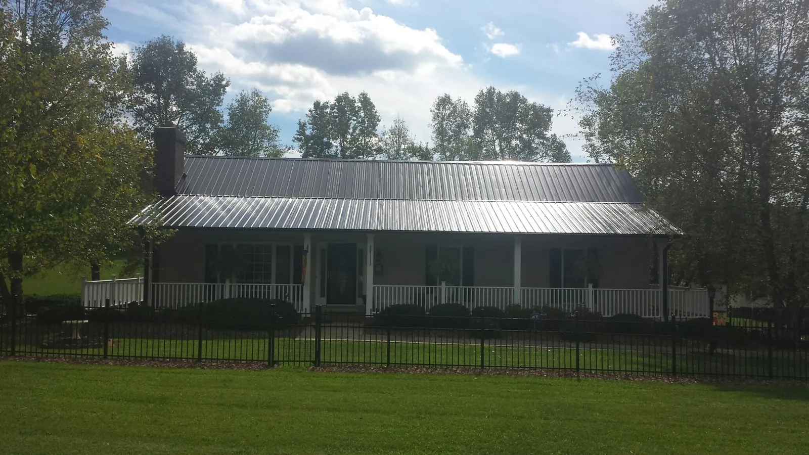 Gray metal roof on a brick ranch with a full width front porch — Gutter Guard Installation work by our crew in Red Rock