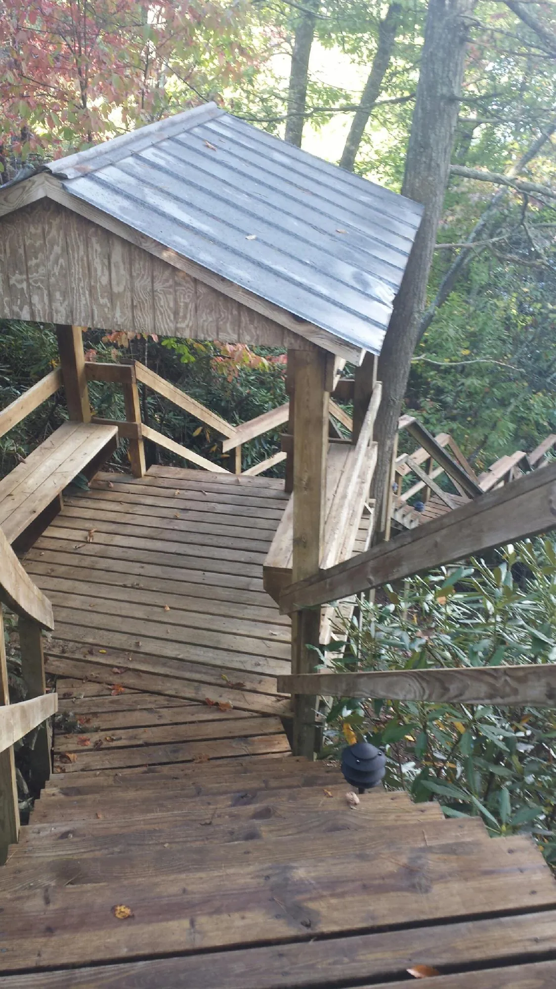 Metal roofed shelter over wooden steps on a wooded walkway — Skylight Repair & Installation work by our crew in Red Rock