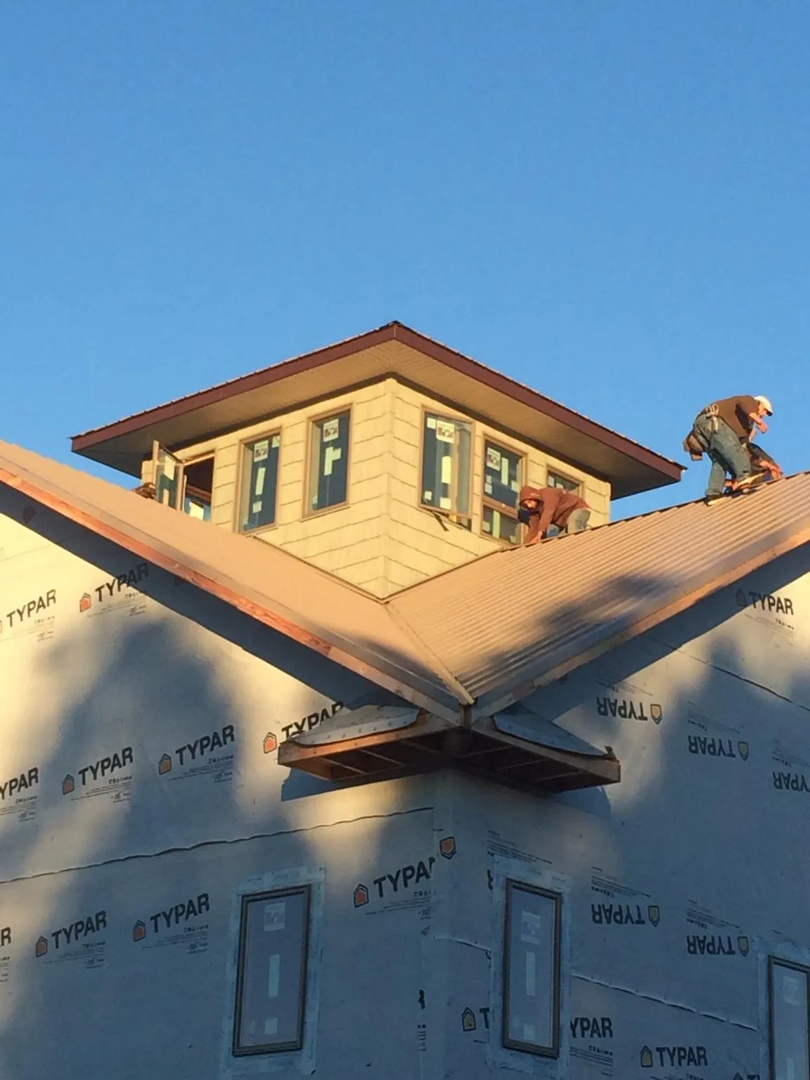Roofers working around a rooftop cupola on a new metal roof at sunset — Roof Waterproofing in Red Rock by Roofing Brothers